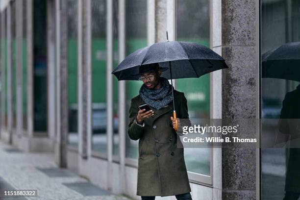 Black Man with Umbrella Texting on Smartphone