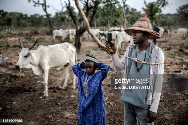 Years-old Fulani herdsman Isa Ibrahim takes pictures of his cattle using his mobile phone during the morning grazing at Kachia Grazing Reserve,...