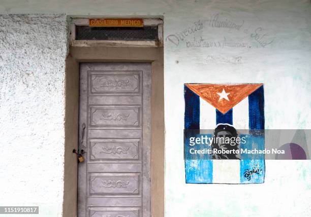 Sign seen on a Cuban house. It has the Cuban flag and an image of Che Guevara on it. The door of the house is made of aluminum produced in a private...