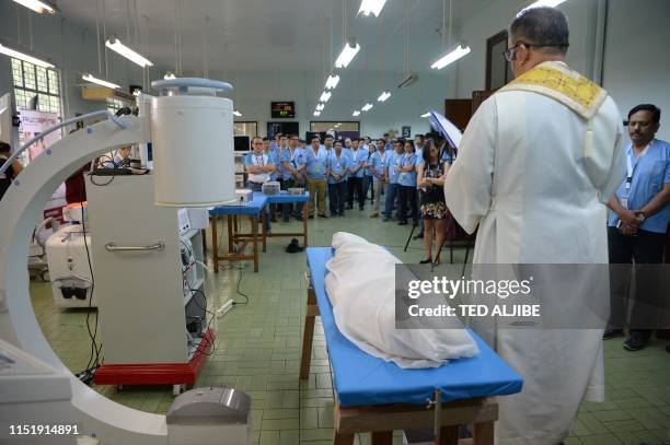 Catholic priest prays next to a cadaver before a spine surgery workshop at the anatomy room of the university in Manila on June 26 as part of the...