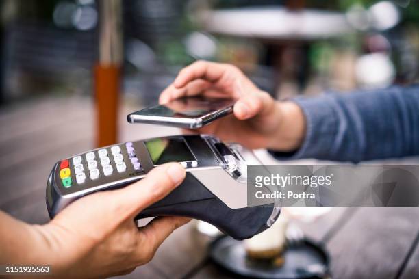 el cliente paga usando el pago móvil al dueño del café - pago por móvil fotografías e imágenes de stock