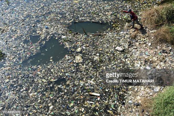Scavenger collects plastic waste for recycling on the Citarum river choked with garbage and industrial waste, in Bandung, West Java province on June...