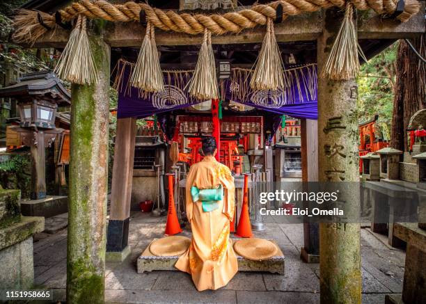 young woman praying at fushimi inari taisha temple, kyoto, japan - shinto shrine stock pictures, royalty-free photos & images