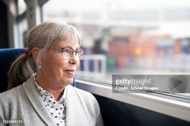 woman in bus looking through window - old woman by window stock-fotos und bilder