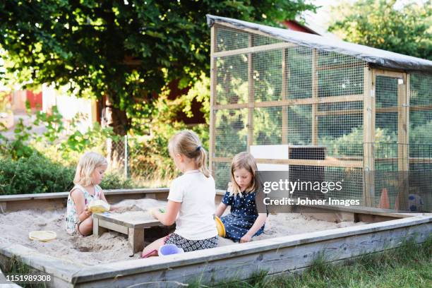 girls playing in sandpit - sandkasten stock-fotos und bilder