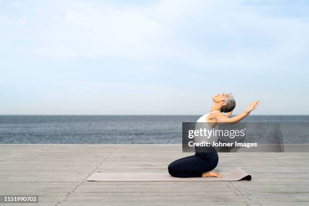 woman practicing yoga on pier - kneeling stock pictures, royalty-free photos & images