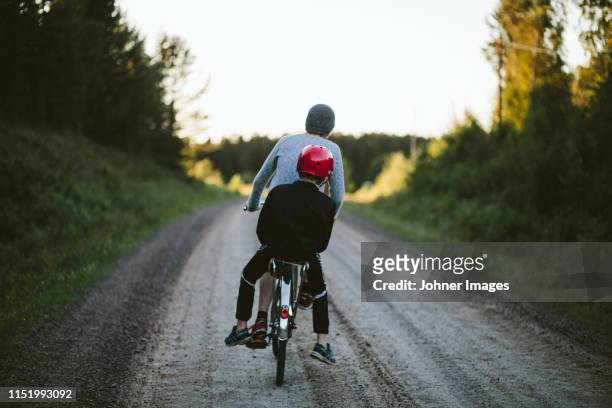 boys riding bike on dirt track - boy in hard hat stock pictures, royalty-free photos & images