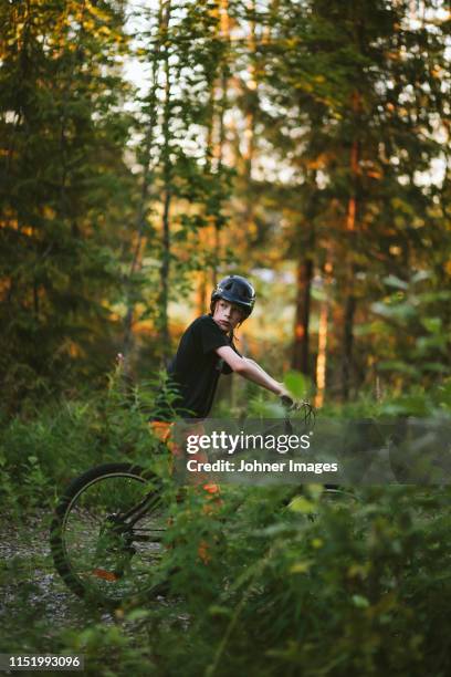boy riding bike in forest - boy in hard hat stock pictures, royalty-free photos & images