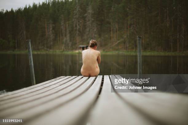 naked woman sitting on jetty - nudity stock pictures, royalty-free photos & images