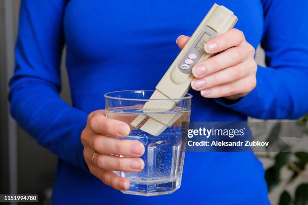 girl lab technician holding a digital tester to determine water quality control and lowers it into a glass of drinking water for analysis, at home, close-up. - ph value stock pictures, royalty-free photos & images