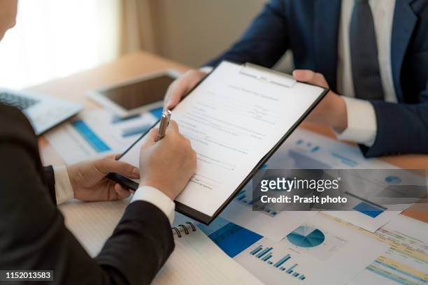 handsome bearded entrepreneur as his business partner finally signing important contract in office. - contract stock pictures, royalty-free photos & images