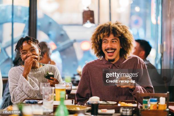 group of friends enjoying at japanese pub - black man eating stock pictures, royalty-free photos & images