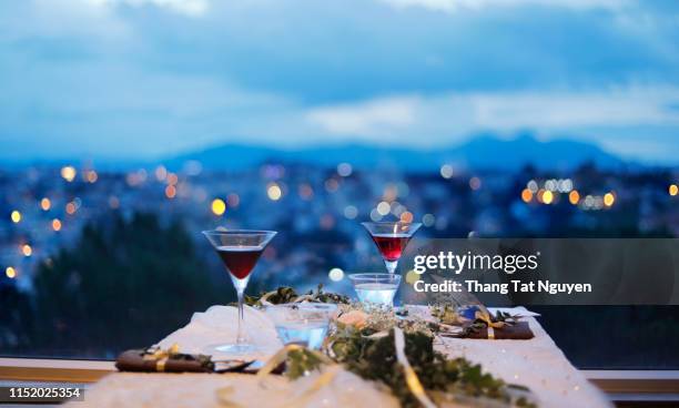 glass of drink by the window with city background at night - restaurant night stock pictures, royalty-free photos & images