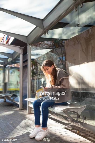 学生のバス待合い所で携帯電話を使用して - bus shelter ストックフォトと画像