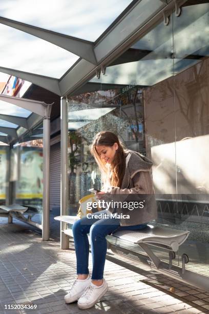 student using mobile at the bus shelter - bus shelter stock pictures, royalty-free photos & images