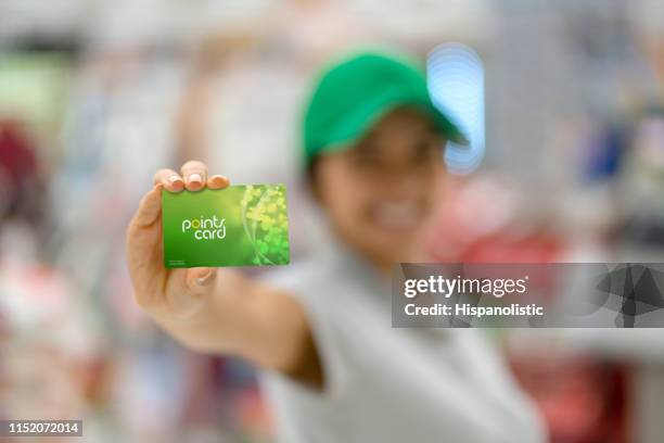 female sales clerk holding an incentive program card at camera - loyalty cards stock pictures, royalty-free photos & images