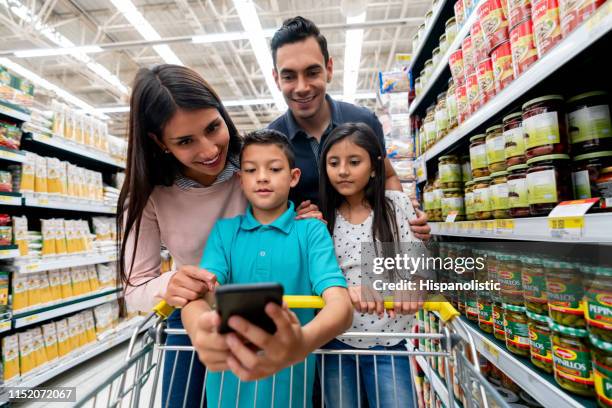 little boy holding smartphone terwijl iedereen kijkt naar de boodschappenlijst - megawinkel stockfoto's en -beelden