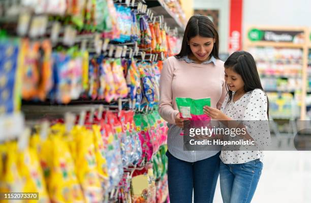 bella madre e figlia che guardano un prodotto al supermercato entrambi sorridenti - bon bon foto e immagini stock