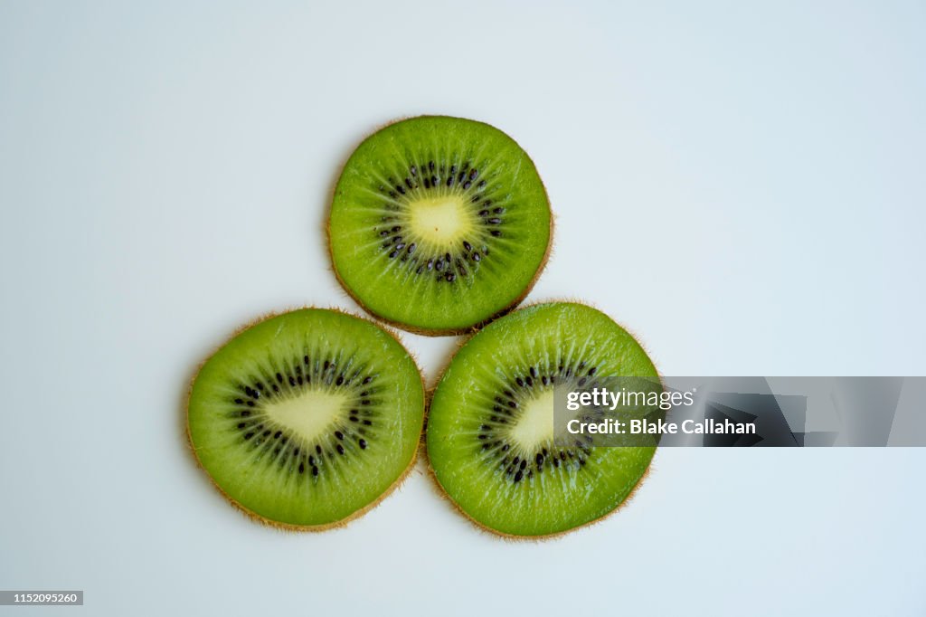 Three kiwi slices on a white background