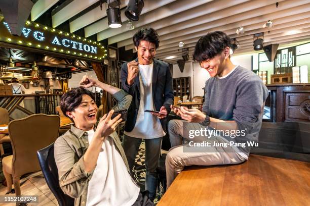 young taiwanese adults playing mobile game at a coffee shop / bar - asian championship stock pictures, royalty-free photos & images