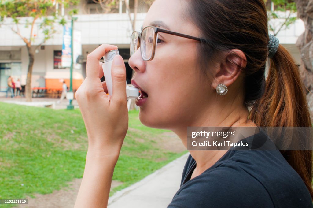 A young woman is using a asthma inhaler