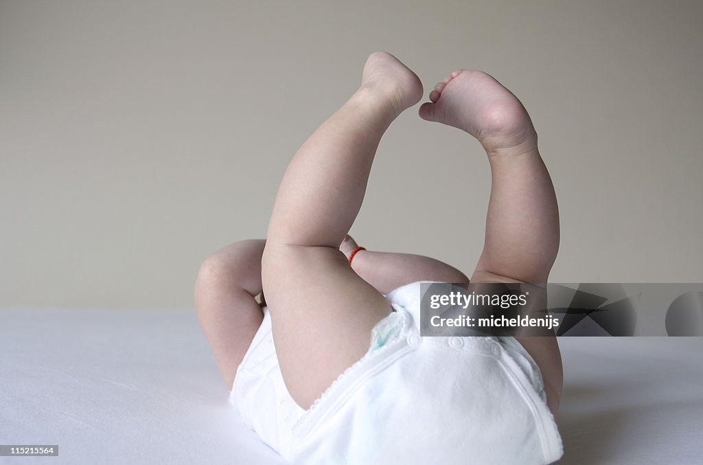Baby Girl In White Onesie With Feet Up