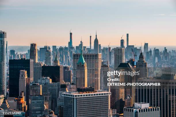 new york city skyline with the trump tower in lower manhattan, taken from a helicopter flying above rooftops at sunrise - wall street lower manhattan stock pictures, royalty-free photos & images