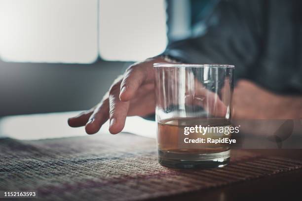 männliche hände greifen nach einem alkoholhaltigen glas - abhängigkeit stock-fotos und bilder