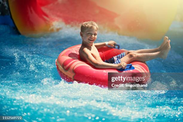 kleiner junge genießt wasserrutsche im wasserpark - rutsche stock-fotos und bilder