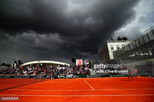 Dark clouds begin to cover the court during the men’s singles first round match between Cameron Norrie of Great Britain and Elliot Benchetrit of...