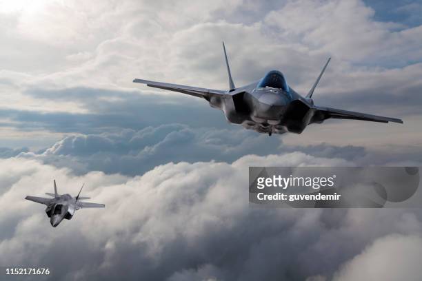 f-35 avión de combate volando sobre las nubes - avión de caza fotografías e imágenes de stock