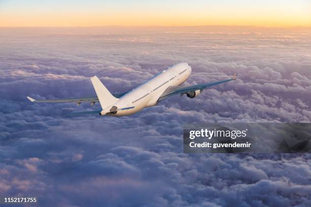 passagierflugzeug fliegt bei sonnenuntergang über wolken - flugzeug seitlich himmel stock-fotos und bilder