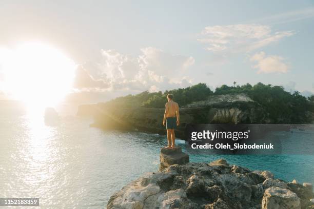 mann springt von der klippe in die blaue lagune auf nusa ceningan - nusa penida stock-fotos und bilder