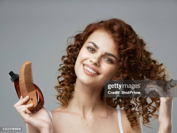 woman with curly hair comb and hair care product - hair products ストックフォトと画像