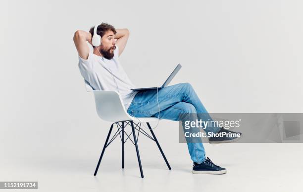 man resting on a chair with a laptop and headphones - man studio shot stock pictures, royalty-free photos & images