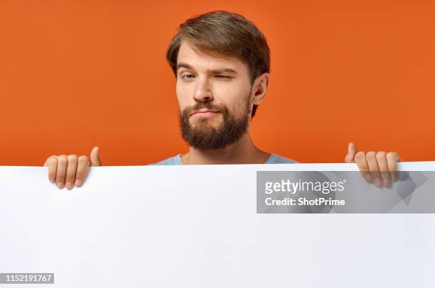 a man holds in his hands a clean sheet, free space for inscriptions. - man studio shot stock pictures, royalty-free photos & images