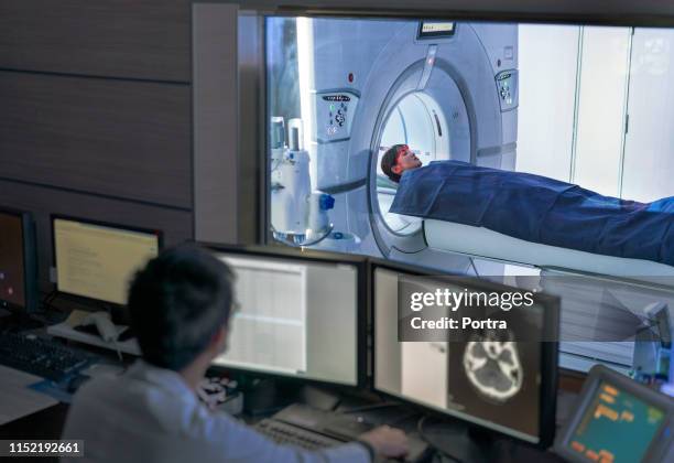 arzt untersucht scan während des patienten im mrt-scanner - magnetresonanztomographie stock-fotos und bilder