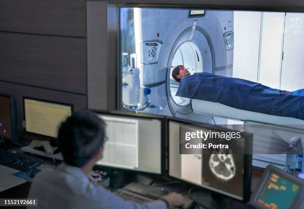 doctor examining scan while patient in mri scanner - exame de ressonância magnética imagens e fotografias de stock