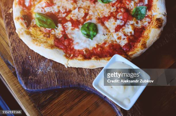 slices of vegetarian pizza with mozzarella cheese, tomatoes, spices and fresh basil. delicious italian pizza. sliced pizza margarita on a wooden board. - pizza crust stock pictures, royalty-free photos & images