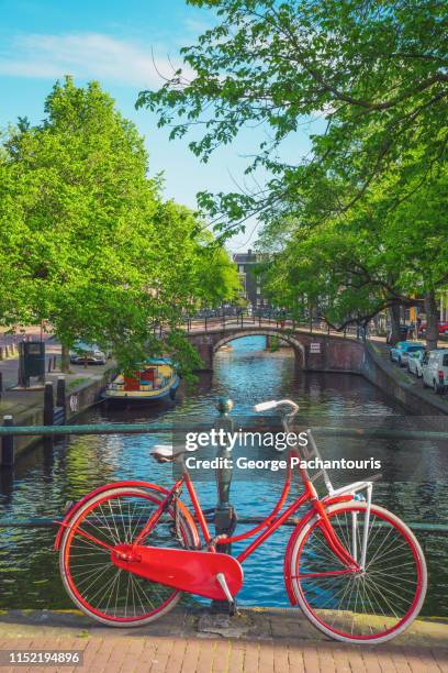 red bicycle on a bridge in amsterdam, the netherlands - amsterdam stock pictures, royalty-free photos & images