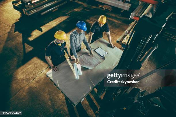 boven mening van manager en handarbeiders die blauwdrukken in een fabriek analyseren. - 2018 blueprint stockfoto's en -beelden