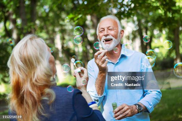 coppia di anziani che si diverte a soffiare bolle - gerontology foto e immagini stock