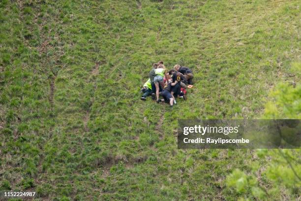 gewonde concurrent wordt behandeld voor een blessure op de 2019 ' cheese rolling ' gehouden op cooper hill, in de cotswolds. - coopers hill cheese rolling and wake stockfoto's en -beelden