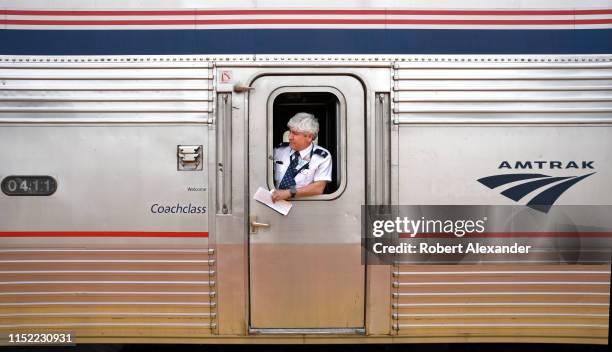 An Amtrak assistant conductor stands at the coach door of a train stopped to pick up and discharge passengers at the railroad station in Lamy, New...