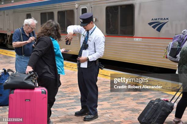 An Amtrak conductor checks e-tickets of passengers preparing to board a train at the depot in Lamy, New Mexico, near Santa Fe. Amtrak's Southwest...