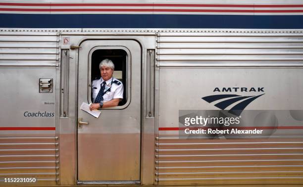 An Amtrak assistant conductor stands at the coach door of a train stopped to pick up and discharge passengers at the railroad station in Lamy, New...
