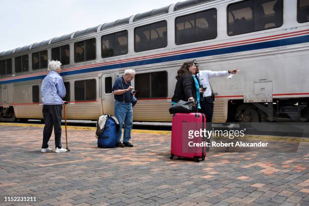 An Amtrak conductor helps passengers board a train at the depot in Lamy, New Mexico, near Santa Fe. Amtrak's Southwest Chief, which transports...