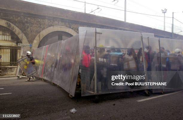 Members of Tutte Bianche use a barricade on wheels to protect themselves as they clash with police during protests against the 27th Group of Eight...