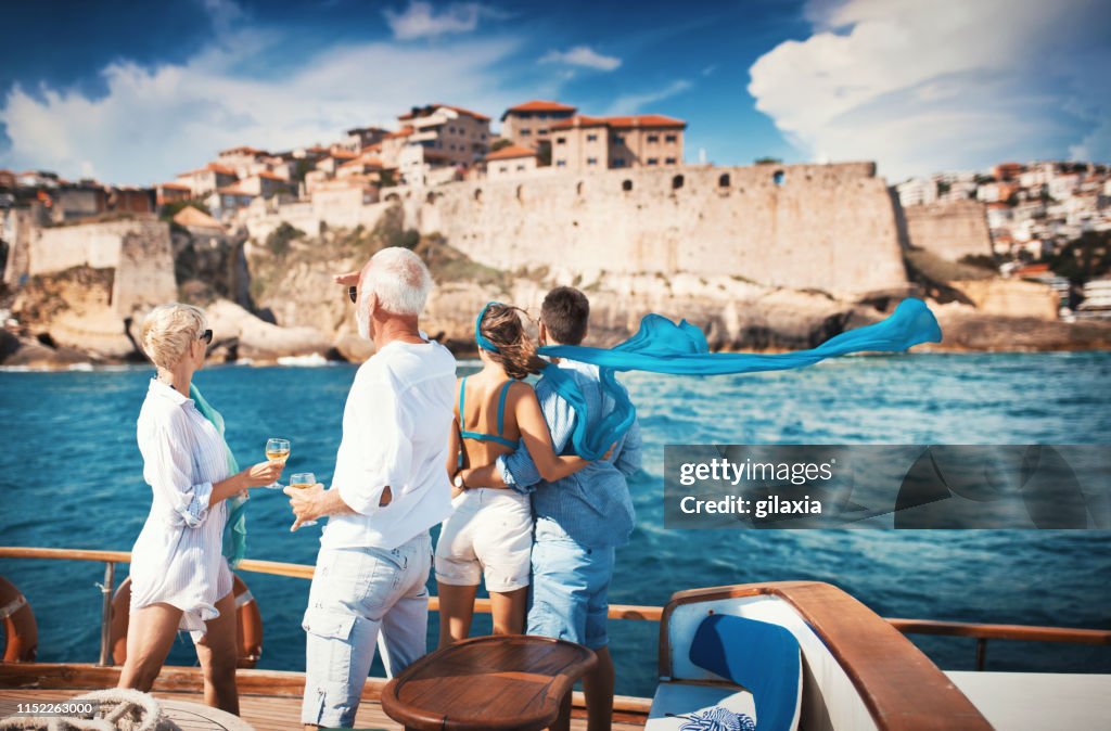 Senior couple on a sailing cruise looking at coastline.