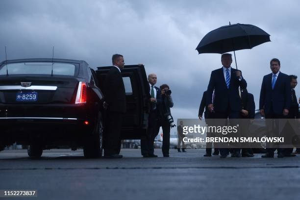 President Donald Trump holds an umbrella as he arrives at Osaka International Airport in Itami, Hyogo prefecture, on June 27, 2019 ahead of the G20...